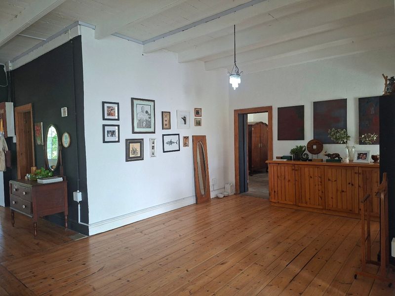 Spacious living area featuring original timber floorboards and exposed ceiling beams, offering a character-filled space with neutral wall finishes.