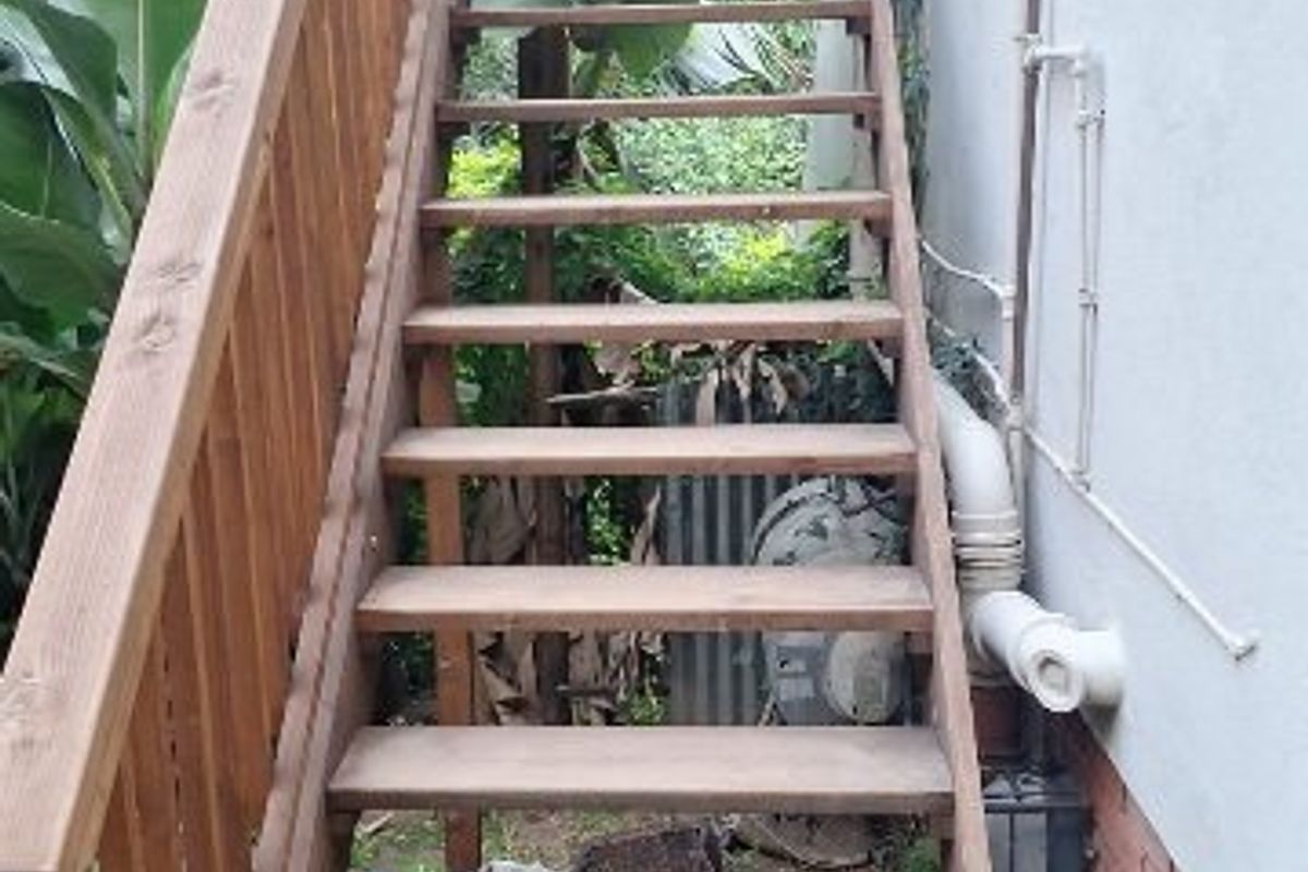 An exterior view of a wooden staircase providing access to the upper level of the apartment building.