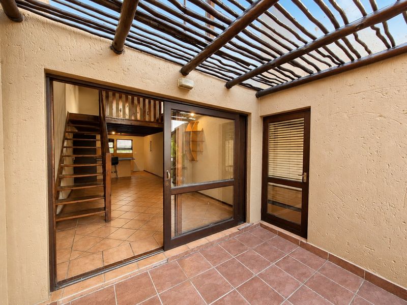 Covered patio area with a wooden pergola, tiled flooring, and direct access to the interior living space via a sliding glass door.