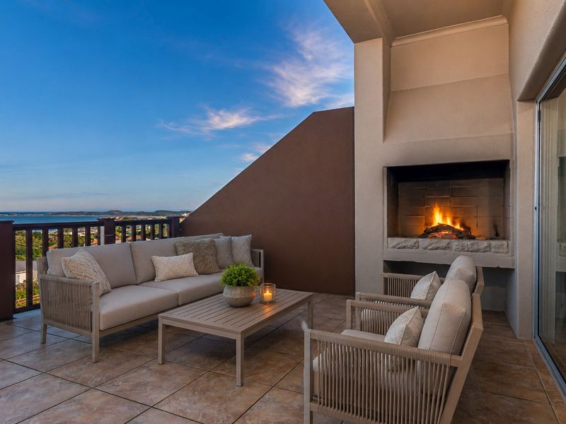 Covered balcony featuring a built-in fireplace, tiled flooring, and scenic coastal views, providing an ideal space for outdoor relaxation.