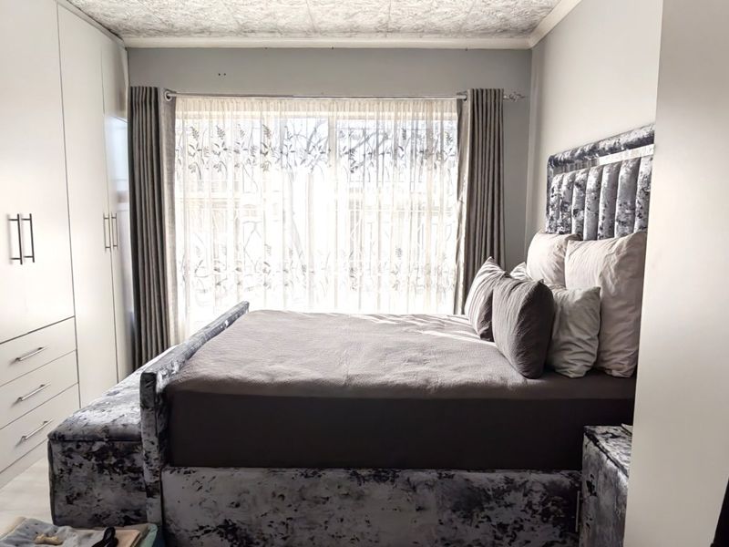 A well-maintained bedroom featuring extensive floor-to-ceiling built-in cupboards and neutral tiled flooring, offering ample storage space.