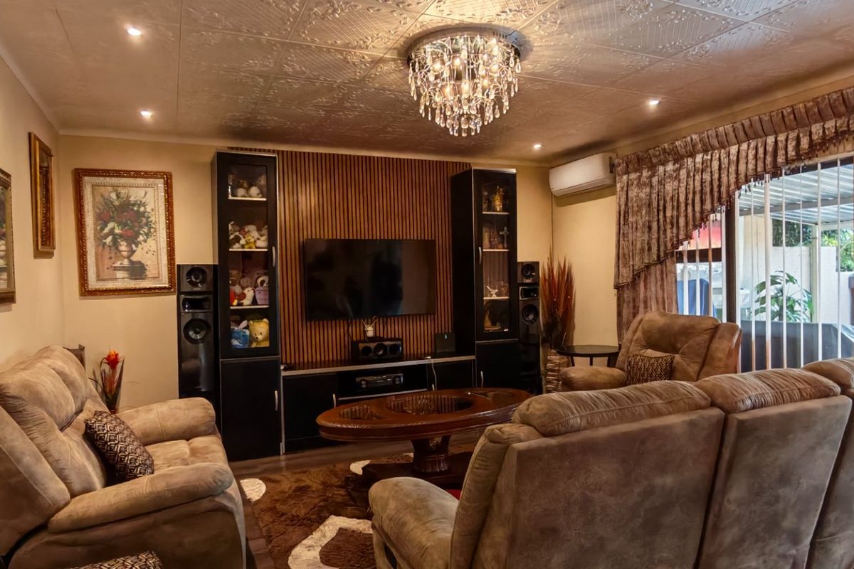 A comfortable living room featuring a decorative slatted wood feature wall, textured ceiling, crystal chandelier, and direct access to the patio through sliding glass doors.