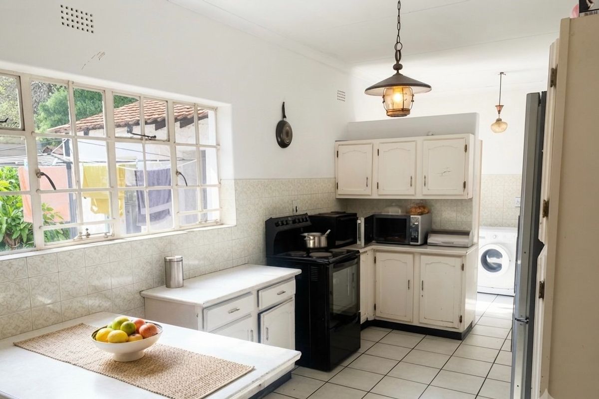 A functional kitchen featuring white cabinetry, tiled backsplash, and tiled flooring, with an adjacent laundry area visible in the background.