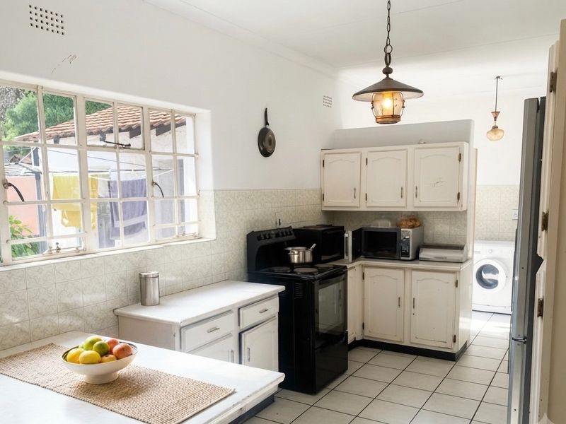 A functional kitchen featuring white cabinetry, tiled backsplash, and tiled flooring, with an adjacent laundry area visible in the background.