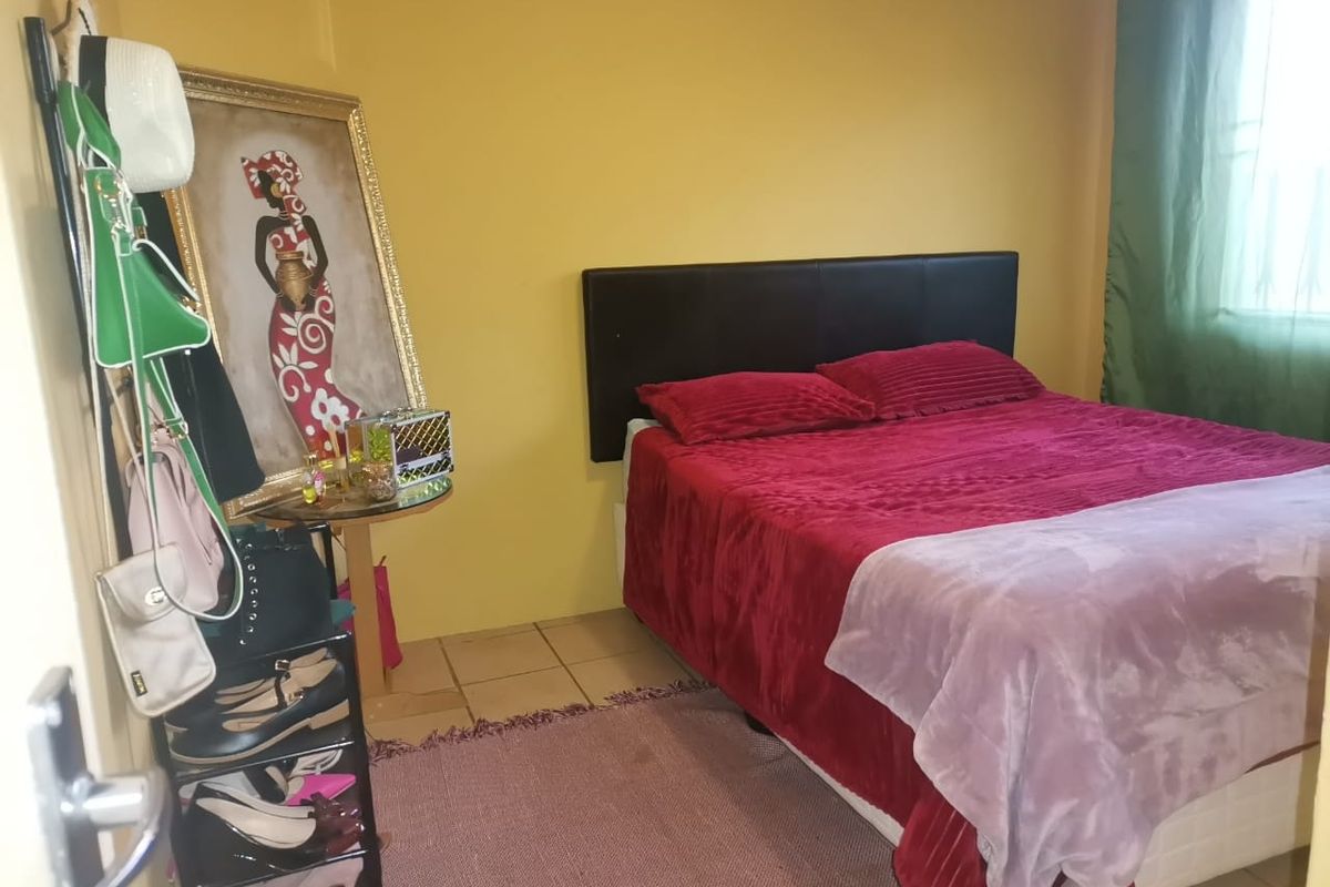 A standard bedroom featuring tiled flooring and yellow painted walls, providing a functional sleeping space.