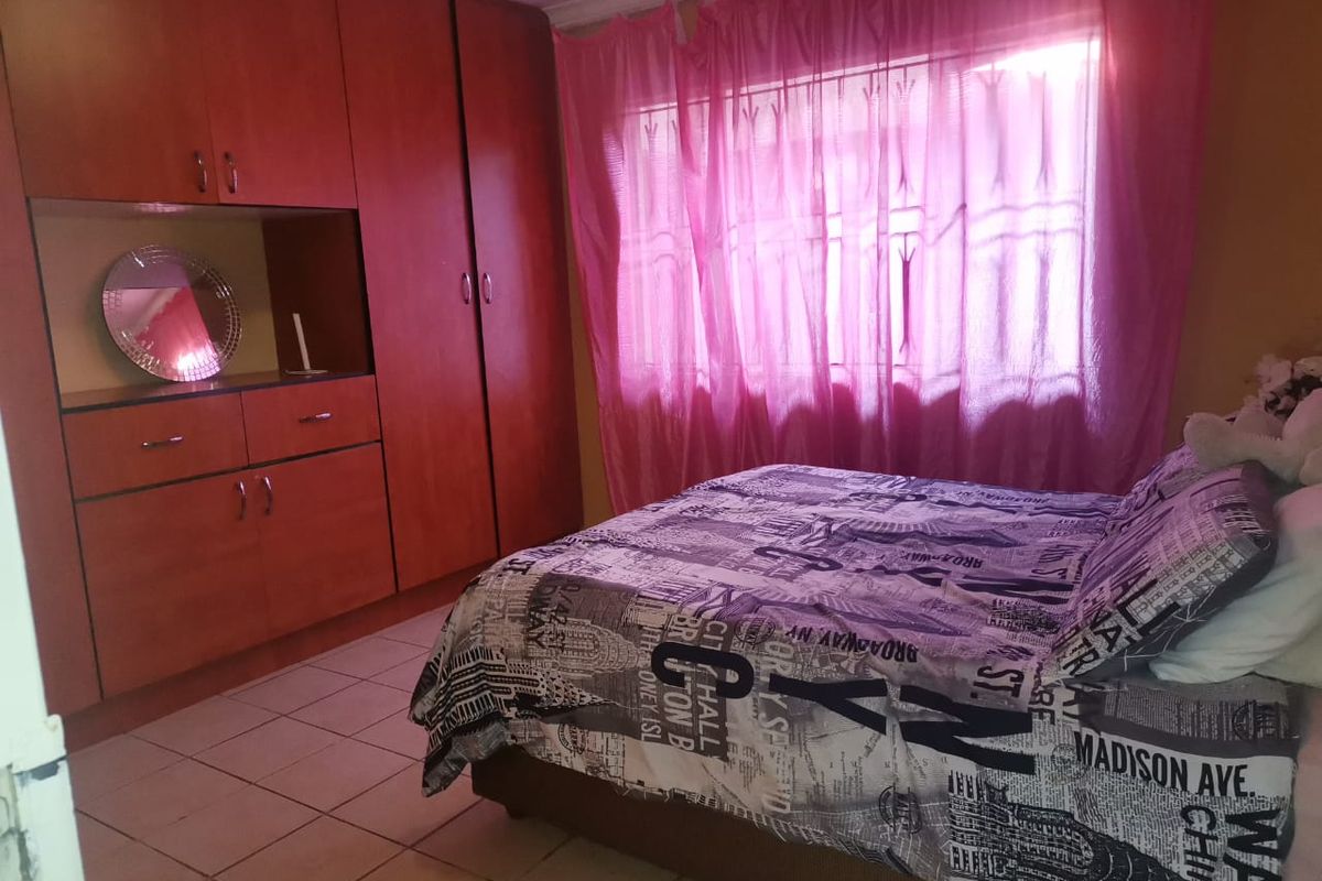 A bedroom featuring built-in wooden cupboards and tiled flooring, providing functional storage space and a neutral foundation for interior updates.
