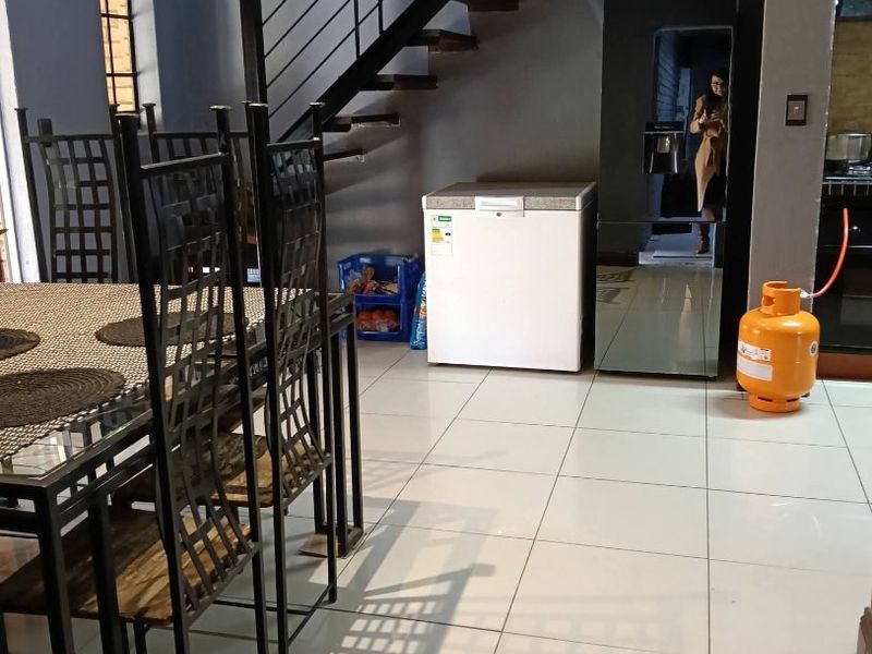 Open plan living area featuring a staircase with a metal balustrade and tiled flooring, providing a functional layout for the townhouse.