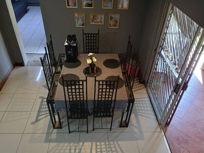 A dining area featuring tiled flooring and a sliding glass door with an integrated security gate, providing access to the exterior.