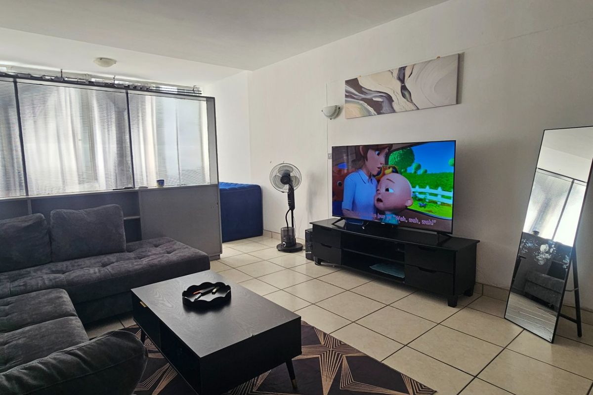 A living room featuring tiled flooring and a partition wall, providing a functional and open living space.