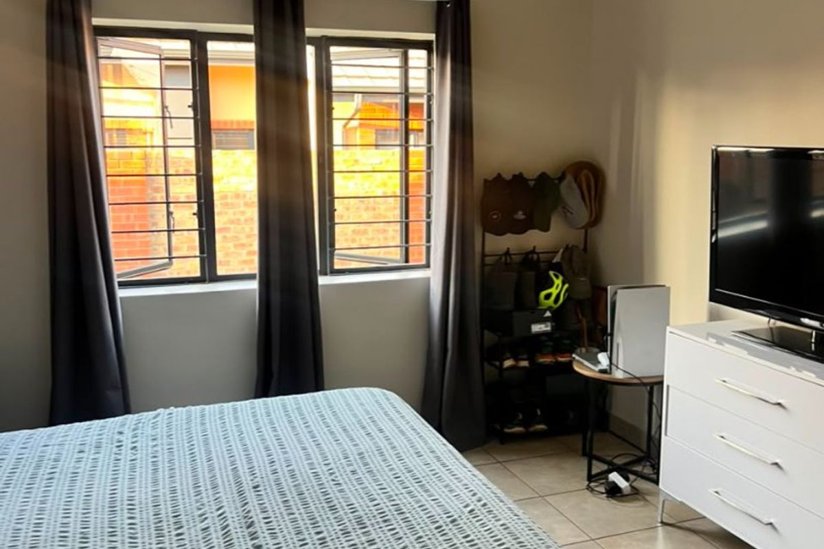 A bedroom featuring tiled flooring, security bars on the windows, and decorative ceiling cornicing.