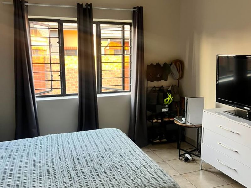 A bedroom featuring tiled flooring, security bars on the windows, and decorative ceiling cornicing.