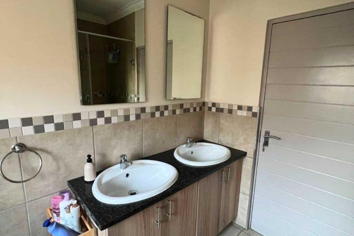 A functional bathroom featuring a double vanity with granite countertops, tiled backsplash, and dual wall-mounted mirrors.