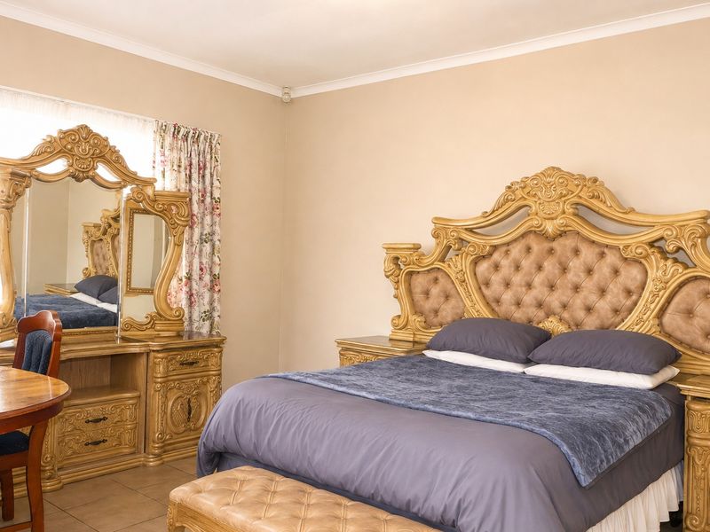 A spacious bedroom featuring neutral wall tones, tiled flooring, and coved ceiling detailing, providing a functional and well-maintained living space.