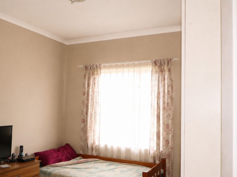 A bedroom featuring neutral wall paint, coving, and a window with a curtain rod.