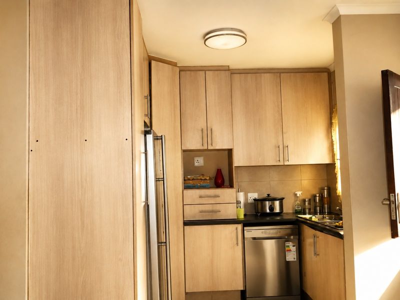 A functional kitchen featuring light wood-finish cabinetry, dark countertops, and integrated appliances, offering a clean and practical workspace.