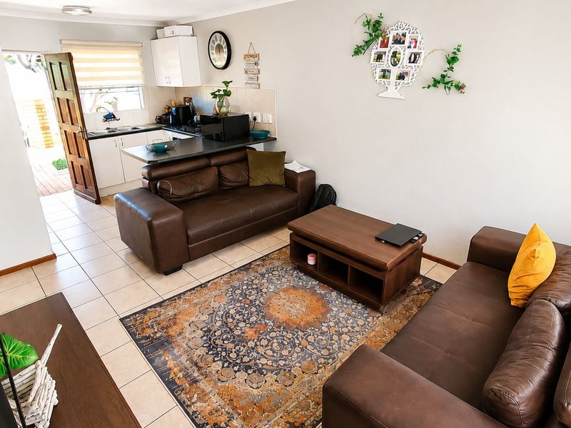 Open plan living area featuring tiled flooring and a functional kitchen with breakfast counter, providing a practical layout for daily living.