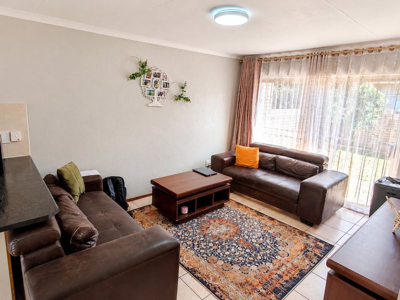 Open-plan living area featuring tiled flooring and a sliding glass door providing access to the exterior, seamlessly connected to the kitchen space.