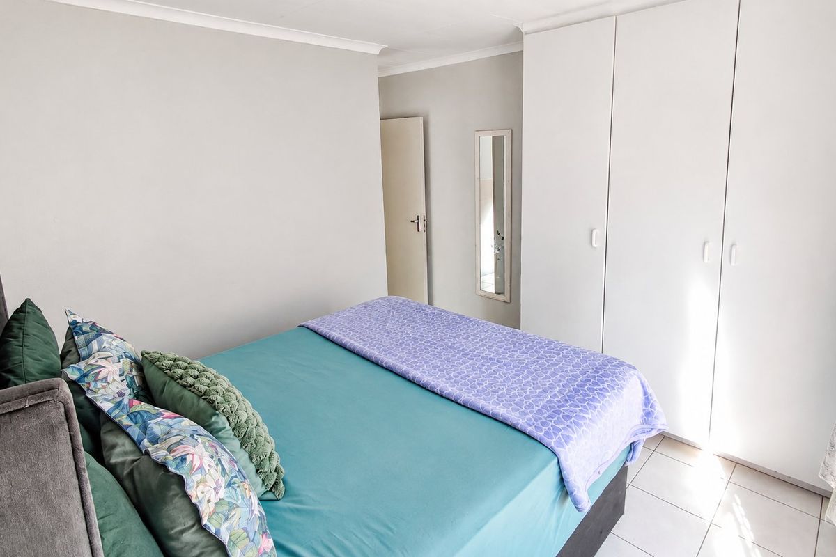 A well-maintained bedroom featuring neutral walls, tiled flooring, and ample built-in cupboard storage.