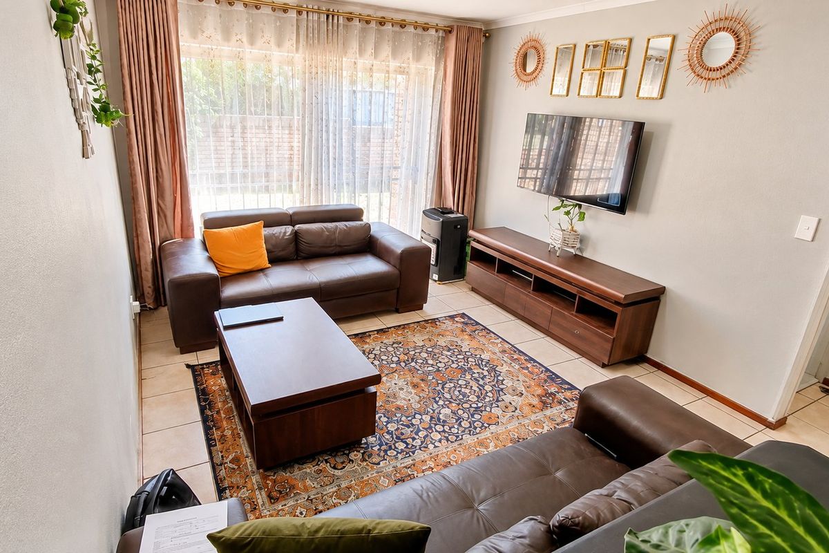 A well-maintained living room featuring tiled flooring and a large sliding glass door that provides natural light and access to the exterior.