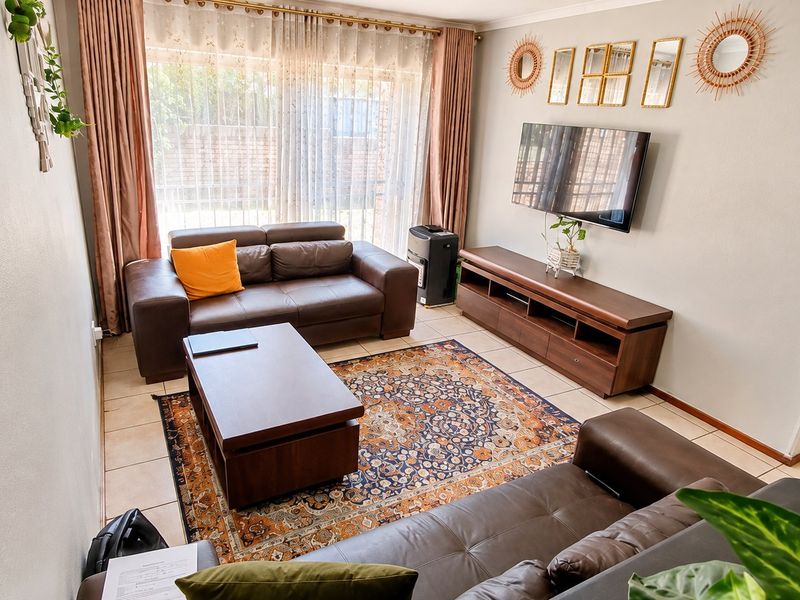 A well-maintained living room featuring tiled flooring and a large sliding glass door that provides natural light and access to the exterior.