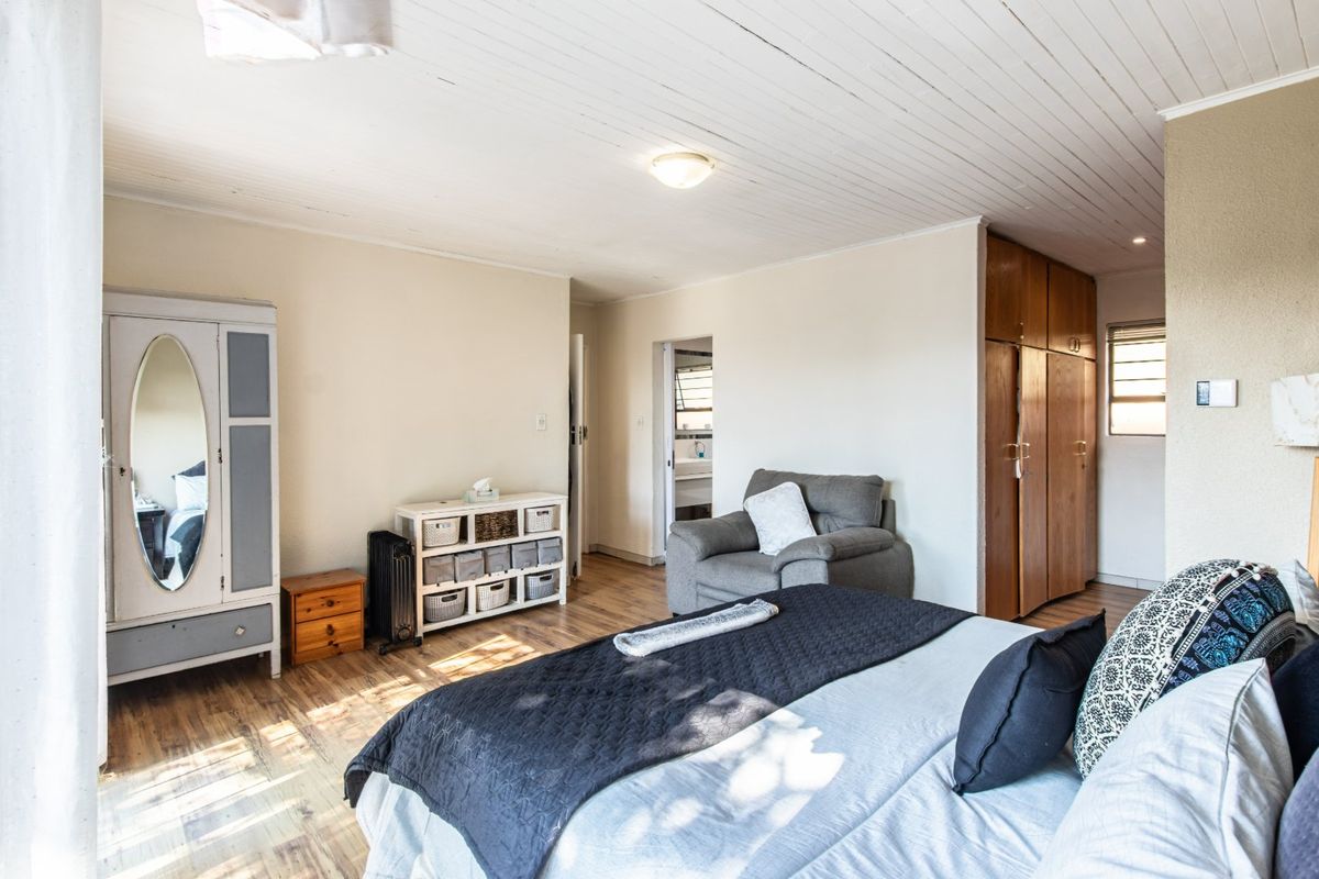 Spacious bedroom featuring laminate flooring, a tongue and groove ceiling, and built-in wooden cupboards for storage.