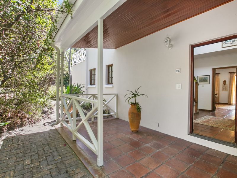 A covered patio entrance featuring tiled flooring, a timber ceiling, and a white balustrade, providing a welcoming transition into the home.