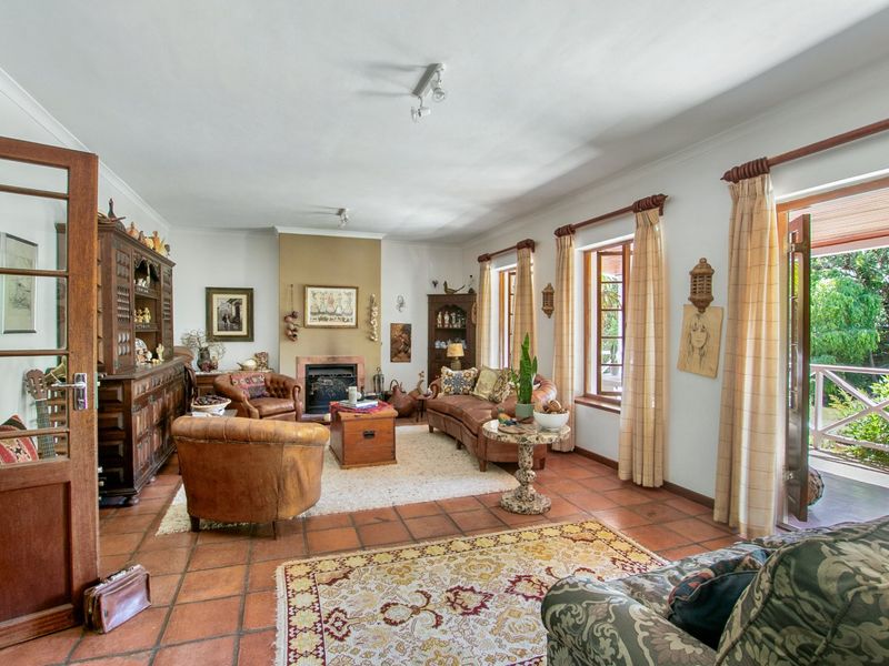 Spacious living room featuring a fireplace, terracotta floor tiles, and direct access to an outdoor patio through timber-framed french doors.