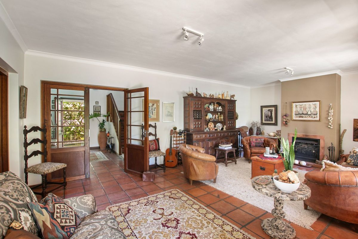 Spacious living room featuring traditional terracotta floor tiles, a built-in fireplace, and timber-framed glass doors leading to the entrance hall.