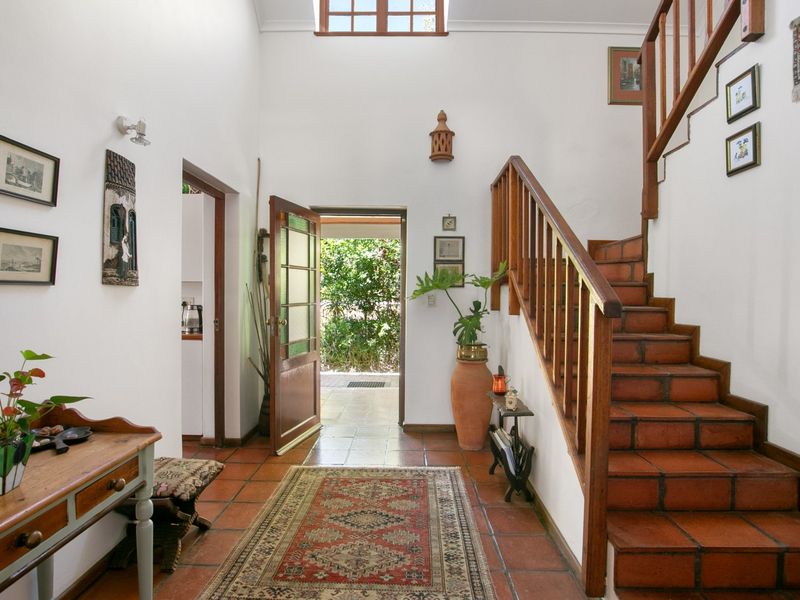 Spacious entrance hall featuring traditional terracotta tile flooring, a timber staircase with balustrade, and a skylight providing natural light.