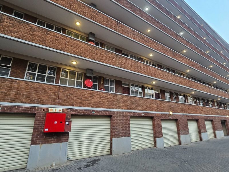 Exterior view of a multi-story commercial building featuring a brick facade, multiple roller shutter garage doors, and integrated fire safety equipment.