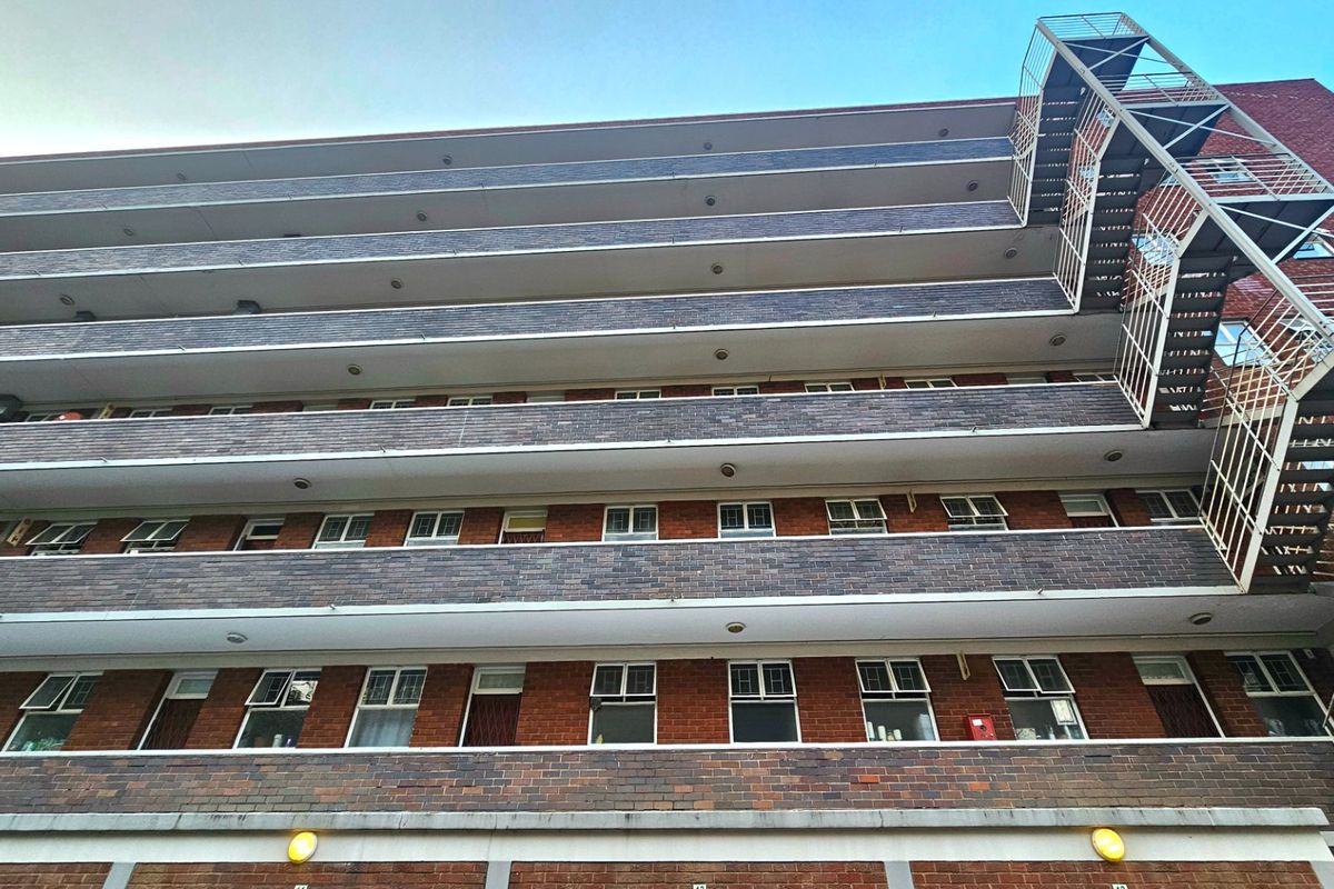 Low-angle view of a multi-story commercial brick building featuring external fire escape stairs and multiple levels of balconies.