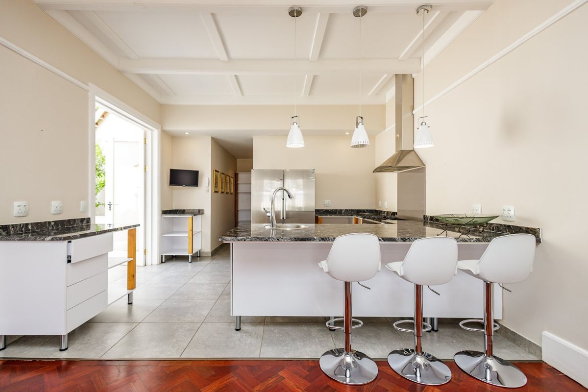 Modern kitchen featuring a central island with granite countertops, stainless steel extractor fan, coffered ceiling, and a blend of tiled and parquet flooring.