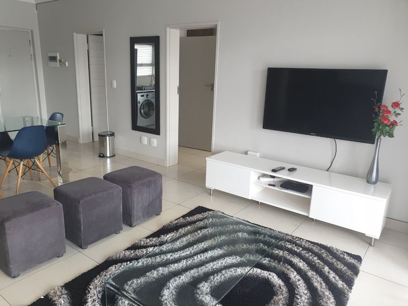 An open-plan living area featuring neutral tiled flooring and direct access to adjacent rooms, providing a functional and well-maintained living space.