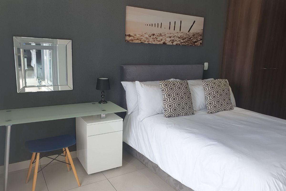 A well-maintained bedroom featuring tiled flooring and a built-in wardrobe, finished with a modern dark accent wall.