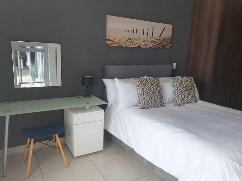 A well-maintained bedroom featuring tiled flooring and a built-in wardrobe, finished with a modern dark accent wall.