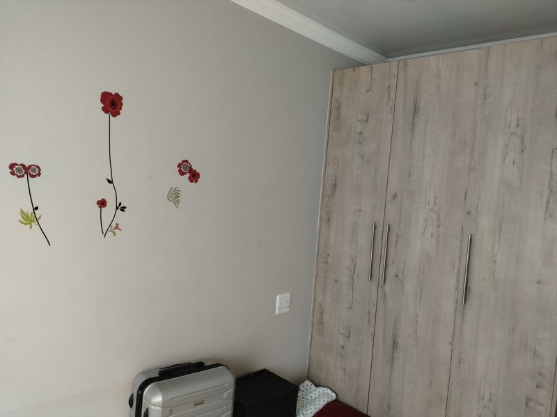 A bedroom featuring light-toned wood-finish built-in cupboards and crown molding, providing functional storage space.