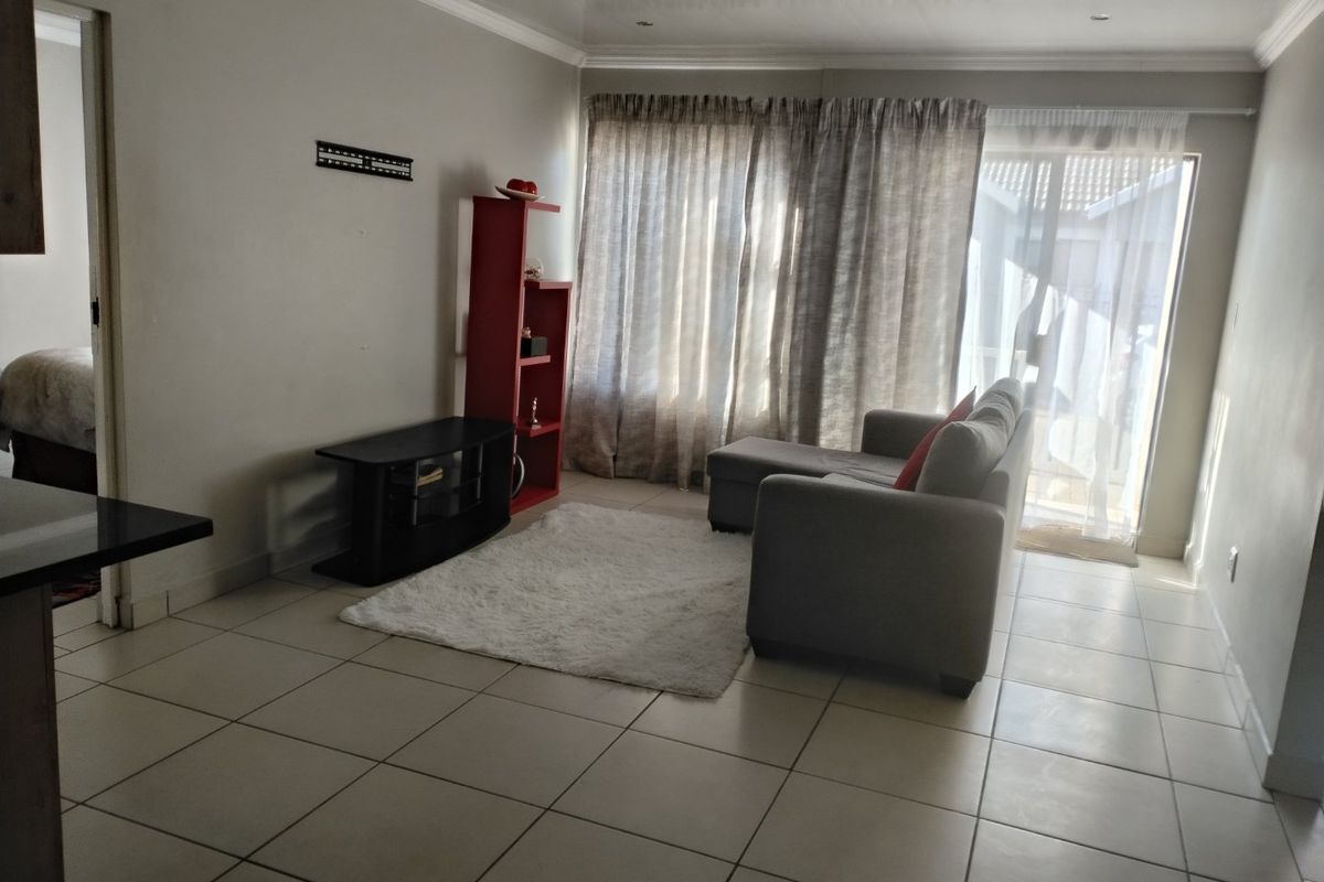 A bright living room featuring tiled flooring, coved ceilings, and a sliding glass door providing access to the exterior.