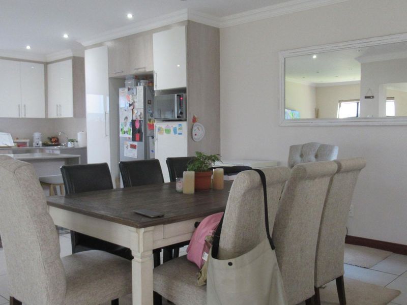 Open plan dining and kitchen area featuring modern cabinetry, a central island, tiled flooring, and recessed lighting.