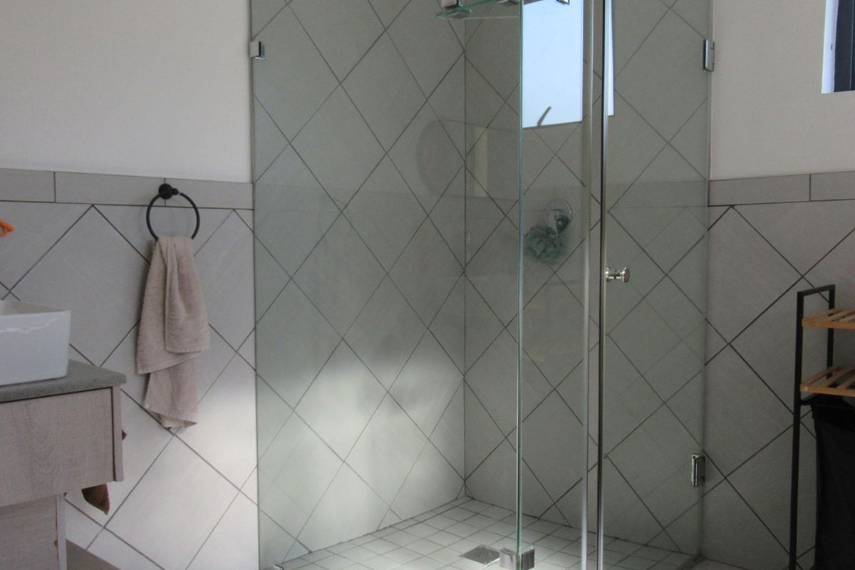 Modern bathroom featuring a glass-enclosed shower, diamond-patterned wall tiling, and a contemporary vessel sink vanity.