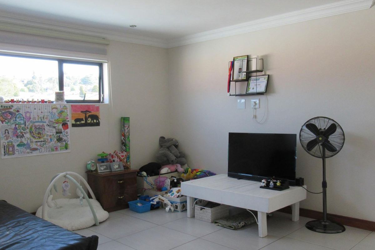 A living room featuring neutral walls, tiled flooring, and decorative cornicing, providing a functional and well-lit space.