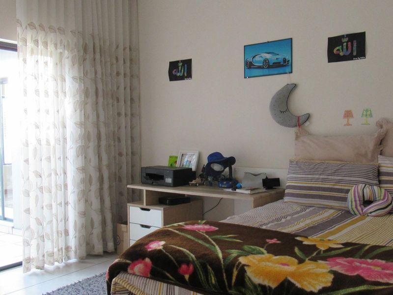 A bedroom featuring tiled flooring and a large sliding glass door providing access to an outdoor patio area.