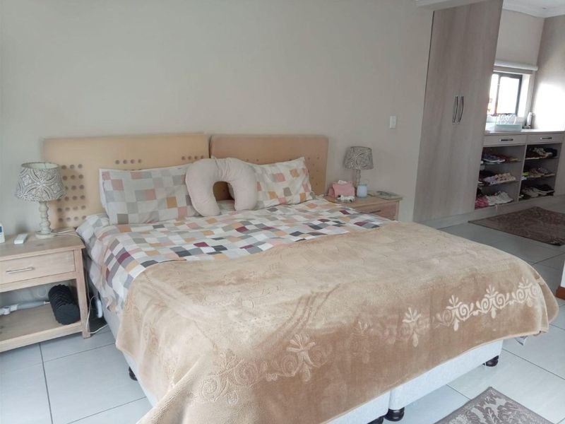 A spacious bedroom featuring neutral tiled flooring and built-in cupboards, offering a functional layout with ample storage space.