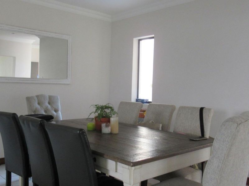 A bright dining room featuring crown molding and a vertical window, providing a clean and neutral space for family meals.