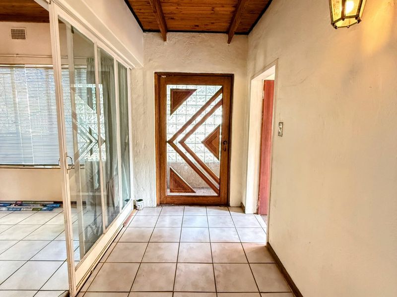 Entrance hall featuring a timber ceiling, ceramic tiled flooring, and a decorative timber front door with glass inserts.