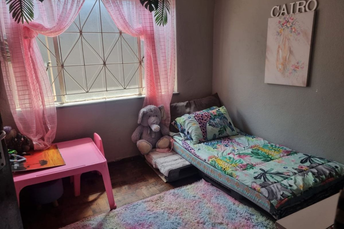 A bedroom featuring a window with security bars and parquet flooring.