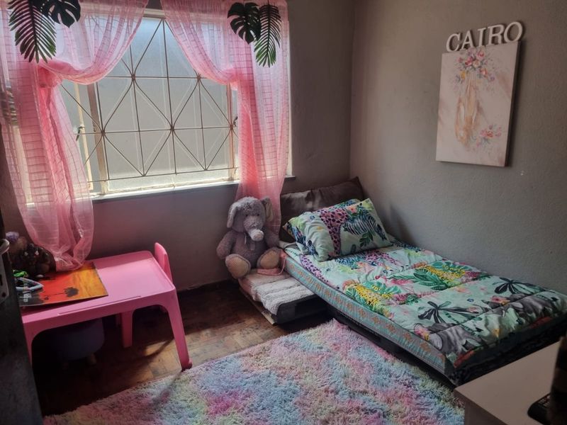 A bedroom featuring a window with security bars and parquet flooring.