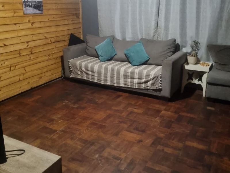 Living room featuring timber wall paneling and traditional parquet flooring, offering a rustic aesthetic with potential for modernization.