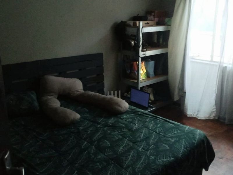 A bedroom featuring timber flooring and natural light from a window.