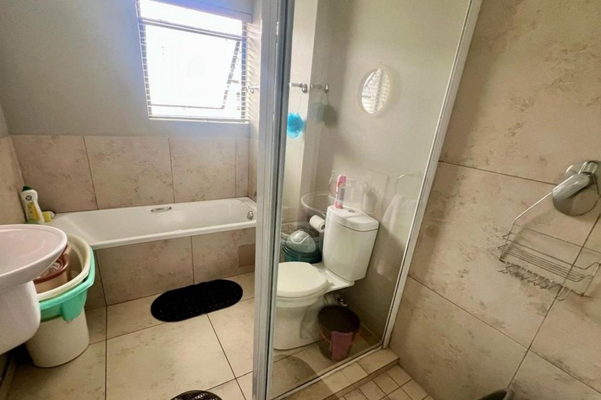 A functional bathroom featuring a bathtub, separate shower enclosure, toilet, and pedestal basin with neutral wall and floor tiling.