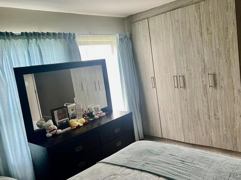 A bedroom featuring light wood-grain built-in cupboards and laminate flooring, offering ample storage space.